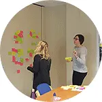 Two women putting coloured post-it notes on a wall