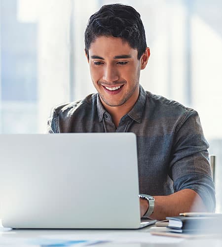 A smiling man using a laptop