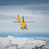 Photo of a helecopter flying over mountains
