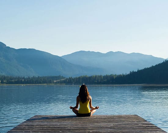 Lady meditating by a lake