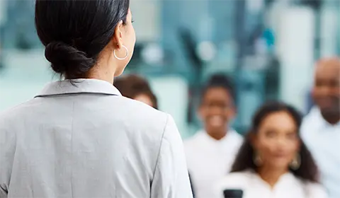 A woman standing in front of people sitting down