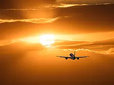 A commercial jet flying at sunset