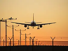 A commercial jet landing at sunset